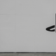 A man looks down at his phone standing alongside a large white wall sporting the Playstation logo.